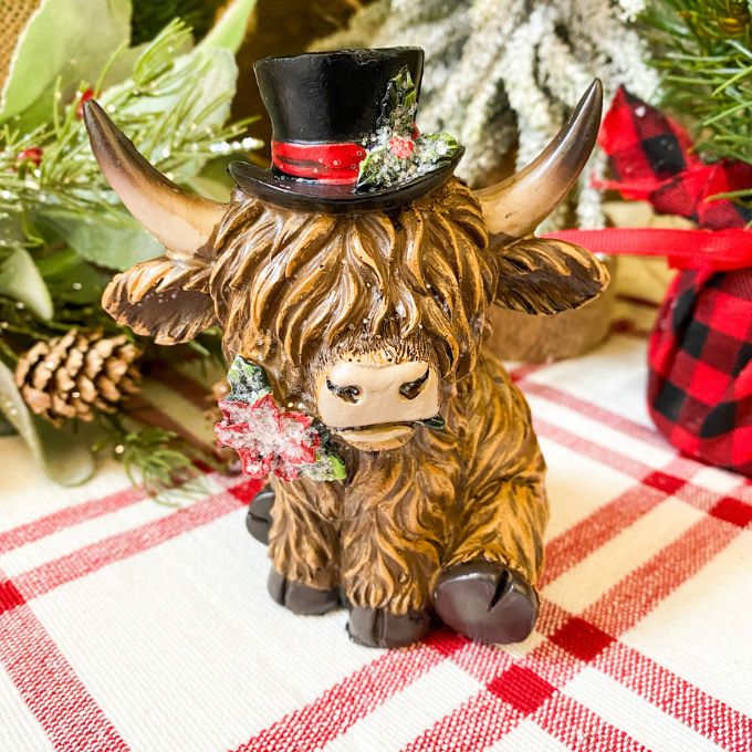 Christmas Highland Cow Figurines - Two Styles are ready for Christmas with their hats - one with a top hat and the other a red Santa Hat. Available at Quilted Cabin Home Decor.