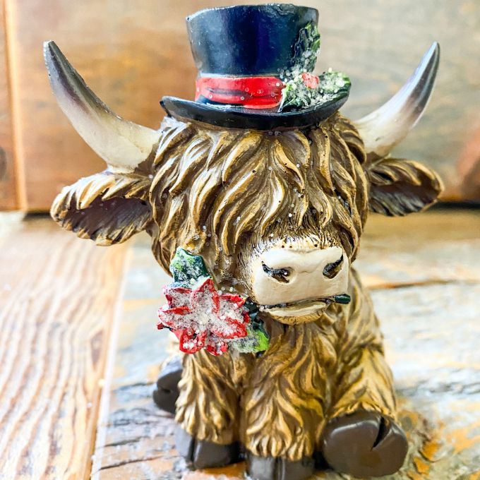 Christmas Highland Cow Figurines - Two Styles are ready for Christmas with their hats - one with a top hat and the other a red Santa Hat. Available at Quilted Cabin Home Decor.