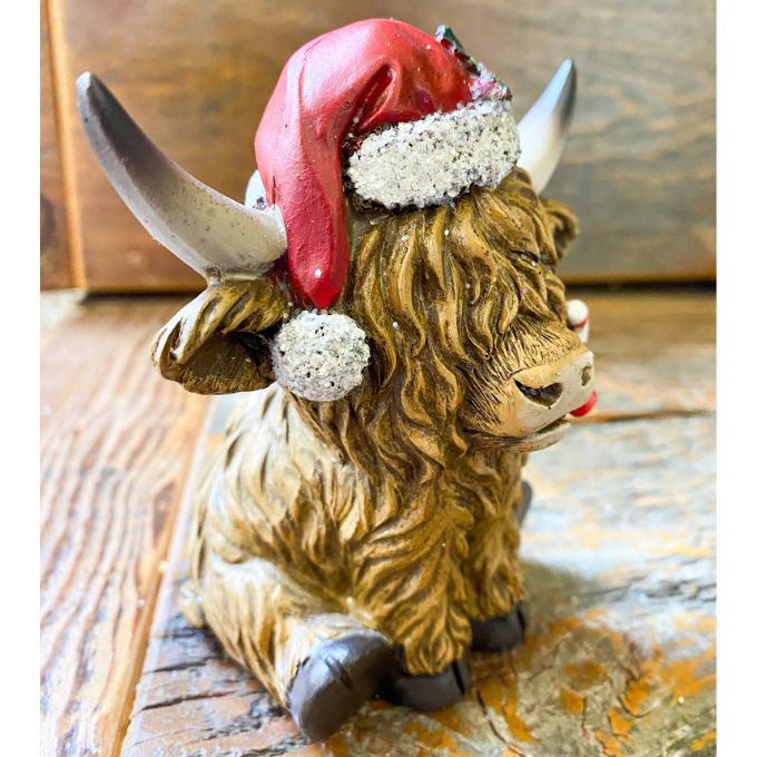 Christmas Highland Cow Figurines - Two Styles are ready for Christmas with their hats - one with a top hat and the other a red Santa Hat. Available at Quilted Cabin Home Decor.