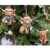 Three Highland cow ornaments on a Christmas tree with festive attire. Highland Cow Ornaments - Three Styles available at Quilted Cabin Home Decor.