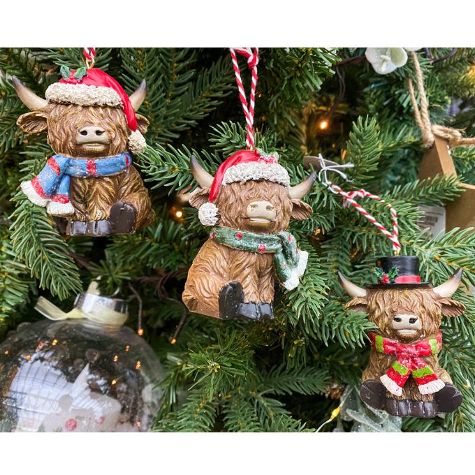 Three Highland cow ornaments on a Christmas tree with festive attire. Highland Cow Ornaments - Three Styles available at Quilted Cabin Home Decor.