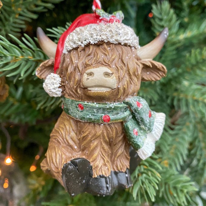 Decorative Highland cow ornament with a Santa hat and green scarf on a Christmas tree. Highland Cow Ornaments - Three Styles available at Quilted Cabin Home Decor.