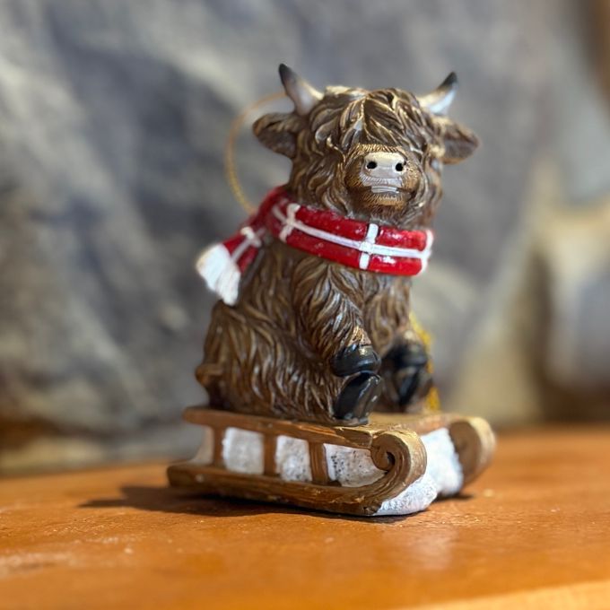Highland Cow with red scarf on sled ornament available at Quilted Cabin in Airdrie