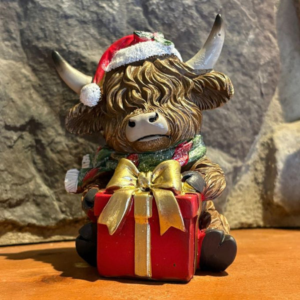 Highland Cow holding a christmas present ornament available at Quilted Cabin in Airdrie