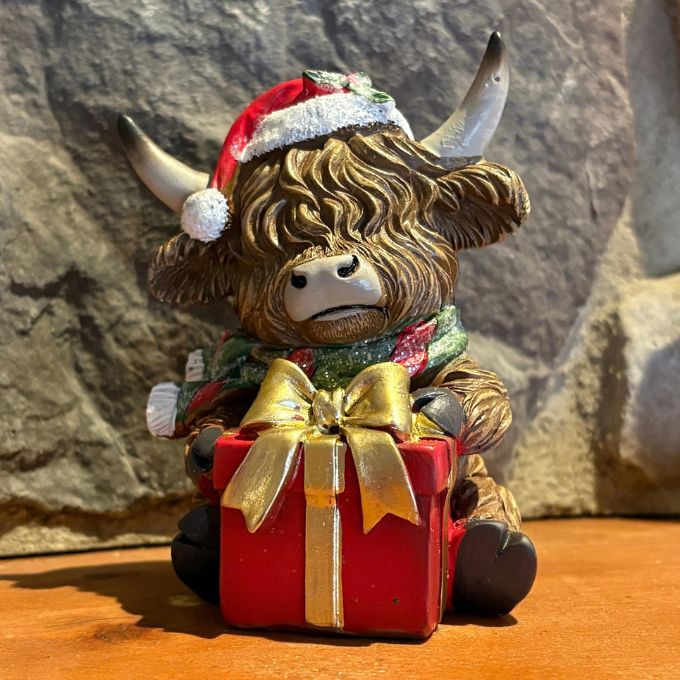 Highland Cow holding a christmas present ornament available at Quilted Cabin in Airdrie