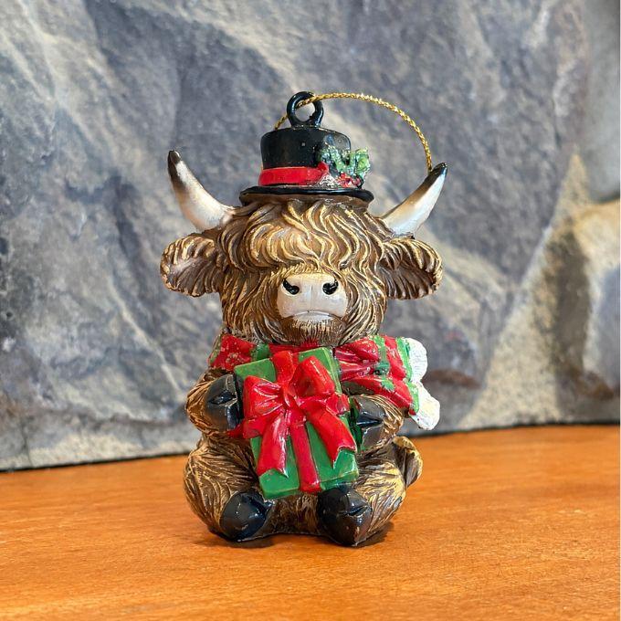 Highland cow with top hat holding a present ornament available at Quilted Cabin in Airdrie