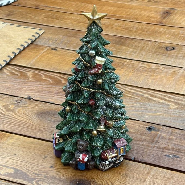 A small decorative Christmas tree figurine with a gold star topper, green textured branches, gold bead garland, red ornaments, and miniature holiday decorations at the base.  Star Topped Tree is available at Rustic Ranch Furniture in Airdrie