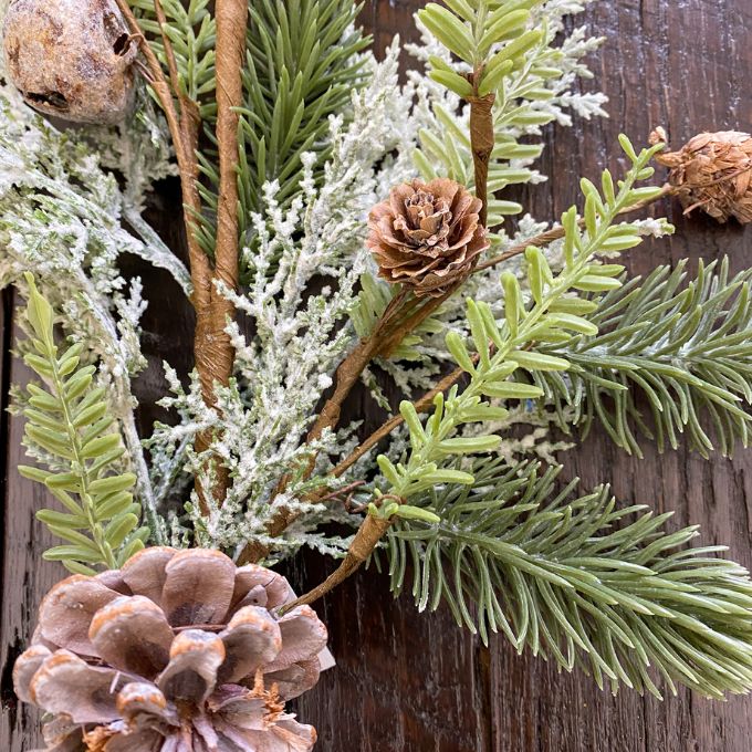 Decorative arrangement of greenery and pinecones on a wooden surface.  Frosted Cedar & Pine Spray - 30" tall available at Quilted Cabin Home Decor.