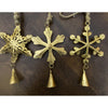 Three gold snowflake-shaped ornaments with bells on a dark brown background.  Vintage Gold Snowflake Ornaments - Set of Three available at Quilted Cabin  Home Decor.