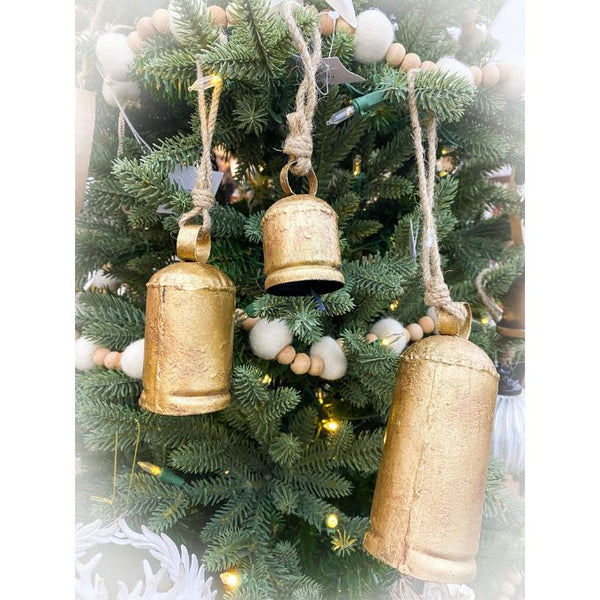 Gold bell ornaments hanging on a decorated Christmas tree. Gold Clapper Bells - Three Sizes available at Quilted Cabin Home Decor.