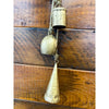 Decorative metal bells hanging on a wooden wall. Mixed Gold Bells Hanger available at Quilted Cabin Home Decor.