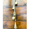 Decorative hanging bells on a wooden wall. Mixed Gold Bells Hanger available at Quilted Cabin Home Decor.