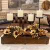 A rustic fall centerpiece arrangement in a wooden rectangular box, featuring dried sunflowers, eucalyptus leaves, and three black metal candle holders with white pillar candles, set in front of a brown leather tufted sofa.  All items available at Rustic Ranch Furniture and Quilted Cabin in Airdrie