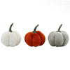 Three small plush pumpkin decorations on a plain white background, shown in white, orange, and light gray, each with a dark stem.  Decorative pumpkins available at Quilted Cabin in Airdrie
