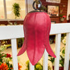 Red tulip bell-shaped object hanging on a white railing with a blurred indoor background Tulip Bells - Three Colours available at Quilted Cabin Home Decor.