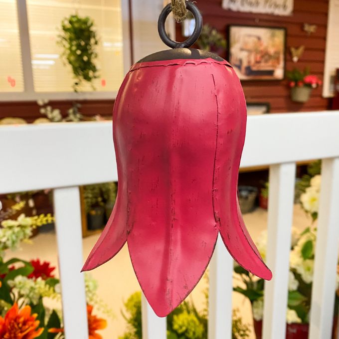Red tulip bell-shaped object hanging on a white railing with a blurred indoor background Tulip Bells - Three Colours available at Quilted Cabin Home Decor.