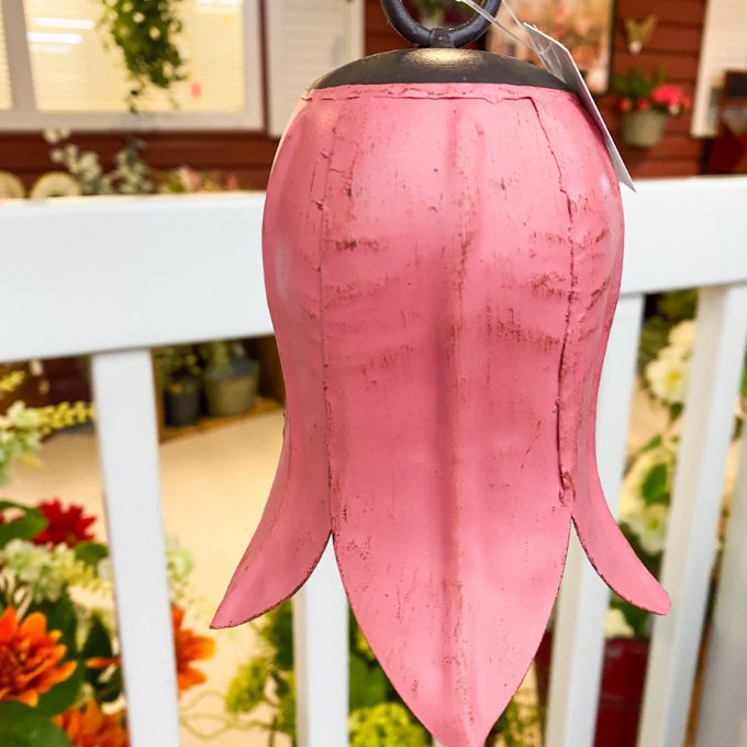 Pink tulip bell hanging on a white railing with a blurred indoor background. Tulip Bells - Three Colours available at Quilted Cabin Home Decor.