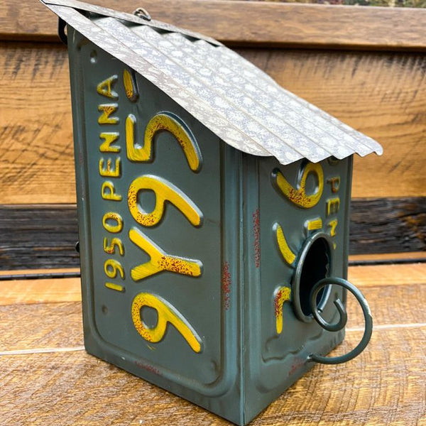 Birdhouse made from a repurposed Pennsylvania license plate on a wooden surface. Recycled License Plate Birdhouse available at Quilted Cabin Home Decor.
