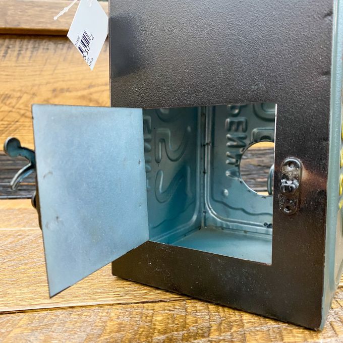 Metallic bird house box with a hinged lid on a wooden surface. Recycled License Plate Birdhouse available at Quilted Cabin Home Decor.