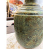 Greenish-brown  metal vaser with a textured surface on a white surface. Rustic Patina Metal Vase  available at Quilted Cabin Home Decor.