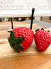 Strawberry-shaped decor pieces. Resin Strawberries - Set of Two available at Quilted Cabin Home Decor.