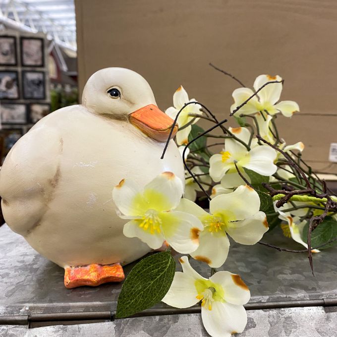 White duck figurine with a floral arrangement on a surface. Chubby White Resin Duck Figurine available at Quilted Cabin Home Decor.