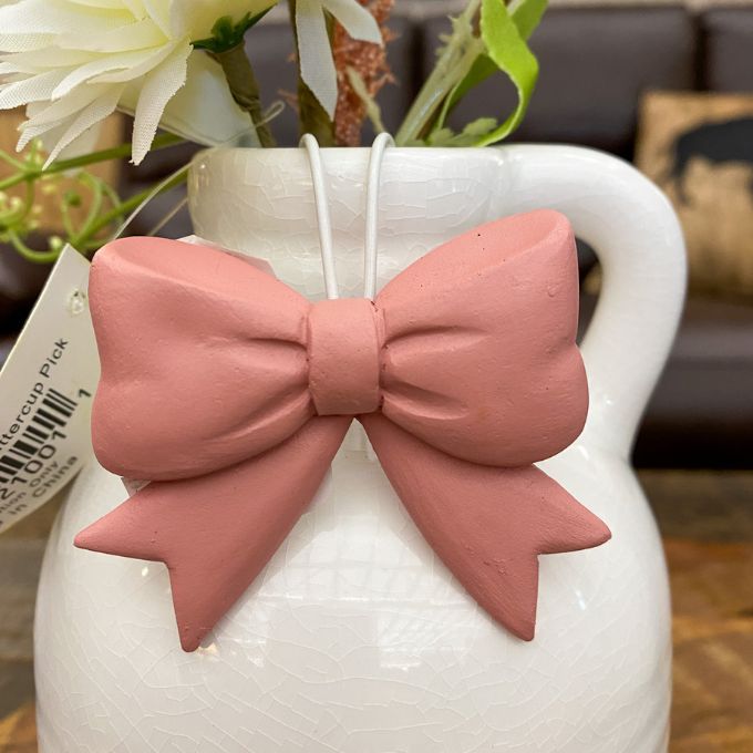 White vase with a pink bow decoration and flowers in the background. Bow Pot Hangers - Three Colours available at Quilted Cabin Home Decor.