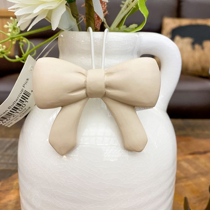 White vase with a beige bow and plant on a wooden surface. Bow Pot Hangers - Three Colours available at Quilted Cabin Home Decor.