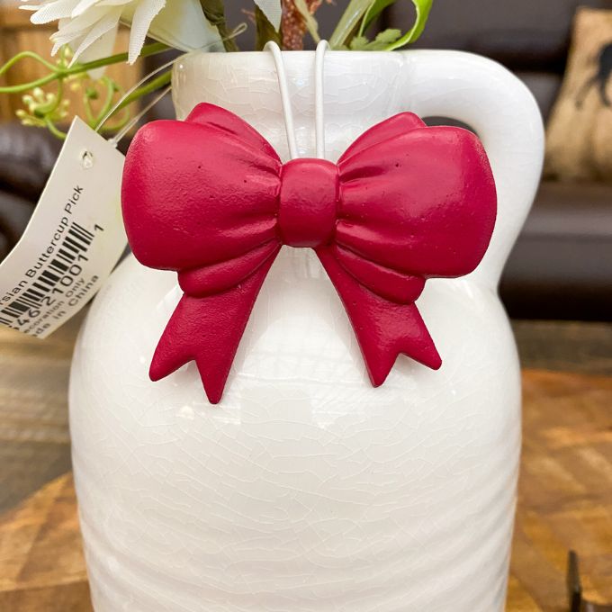 White vase with a red bow and floral arrangement on a wooden surface. Bow Pot Hangers - Three Colours available at Quilted Cabin Home Decor.
