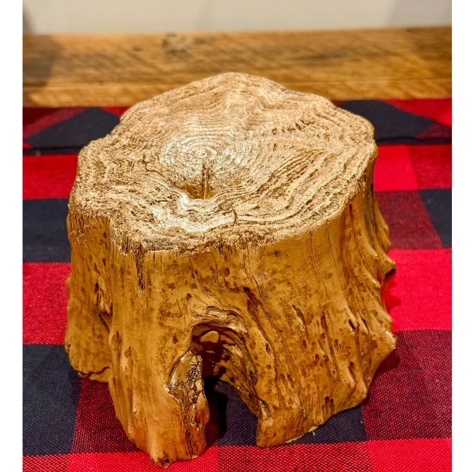 Wooden log stump on a red and blue checkered fabric.   Tree Trunk Riser is available at Quilted Cabin home decor.