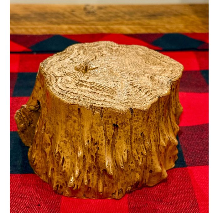 Wooden log stump on a red and blue checkered fabric.   Tree Trunk Riser is available at Quilted Cabin home decor.