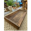 Wooden tray on a textured surface with decorative items in the background.  Reclaimed Wooden Trays come in three sizes and are available at Quilted Cabin Home Decor