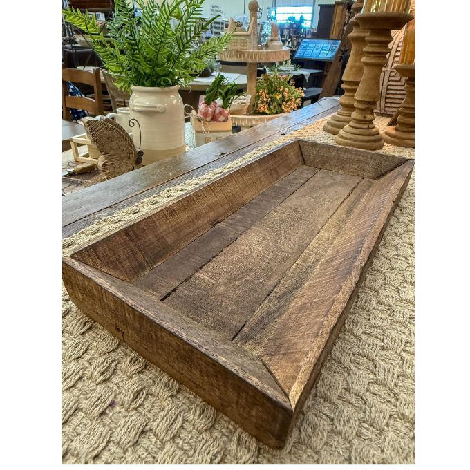 Wooden tray on a textured surface with decorative items in the background.  Reclaimed Wooden Trays come in three sizes and are available at Quilted Cabin Home Decor