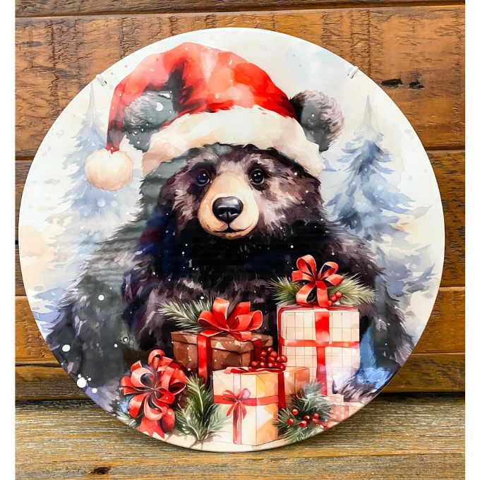 Decorative round hanger with a bear wearing a Santa hat and surrounded by Christmas presents on a wooden background. Christmas Bear Round Wall Hanger available at Quilted Cabin Home Decor.
