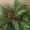 a half sphere floral filled with green thyme leaves and pine cones. Available at Rustic Ranch Furniture and Decor.