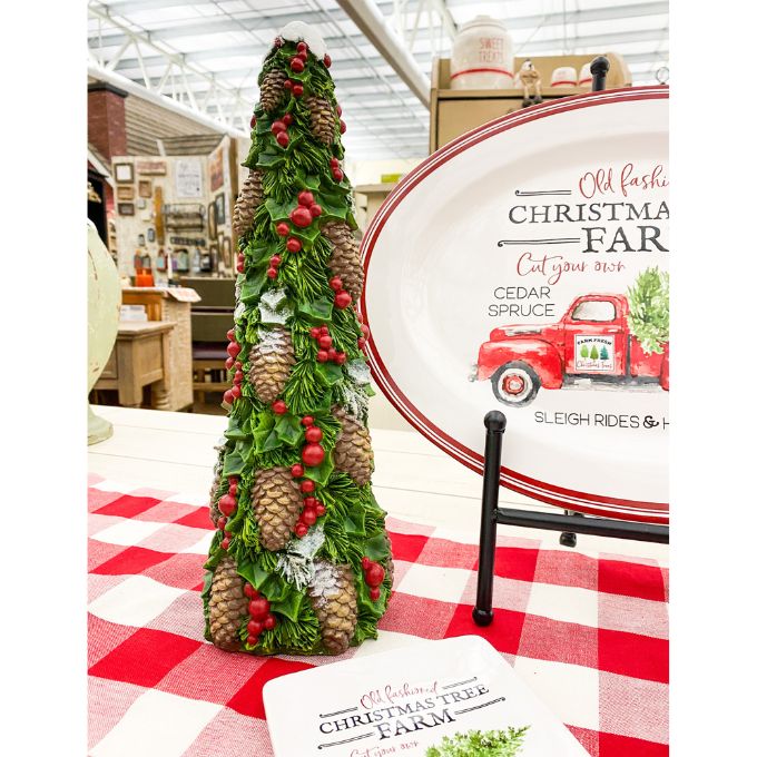 Decorative Christmas tree with pinecones and berries on a red and white checkered tablecloth, with a sign in the background. Pine Christmas Tree Figurine available at Quilted Cabin Home Decor.