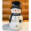 Snowman-shaped lantern with a top hat on a wooden surface. Snowman Lantern available at Quilted Cabin Home Decor.