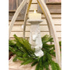Decorative candle holder with a deer design surrounded by greenery against a wooden background. Christmas Deer Pillar Candle Holder available at Quilted Cabin Home Decor.