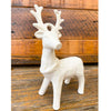 White ceramic deer figurine on a wooden surface. Standing Christmas Deer available at Quilted Cabin Home Decor.