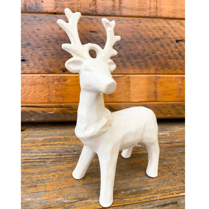 White ceramic deer figurine on a wooden surface. Standing Christmas Deer available at Quilted Cabin Home Decor.