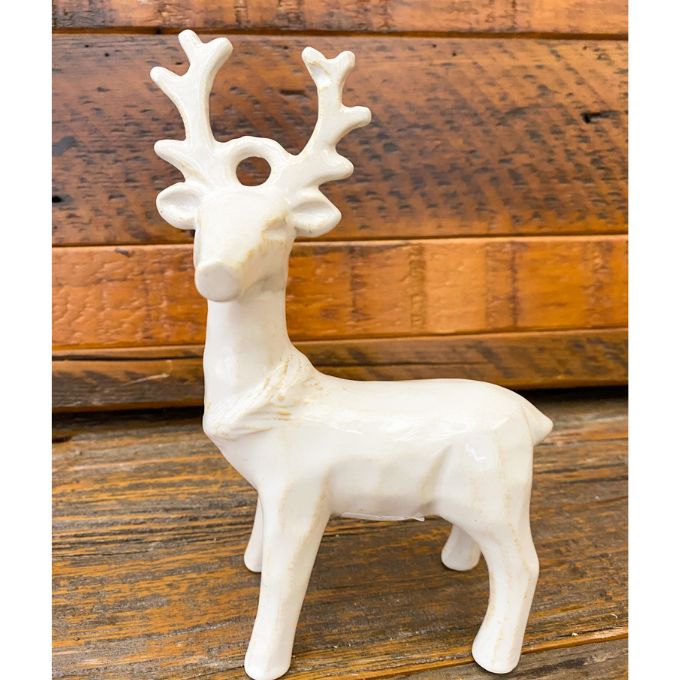 White ceramic deer figurine on a wooden surface. Standing Christmas Deer available at Quilted Cabin Home Decor.