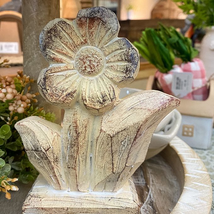 Decorative stone flower figurine on a table with blurred background. Woodgrain Stoneware Flower Figurine available at Quilted Cabin Home Decor.