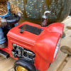 Red tractor figurine on a wooden surface. Highland Cow Tractor Solar Figurine available at Quilted Cabin Home Decor.