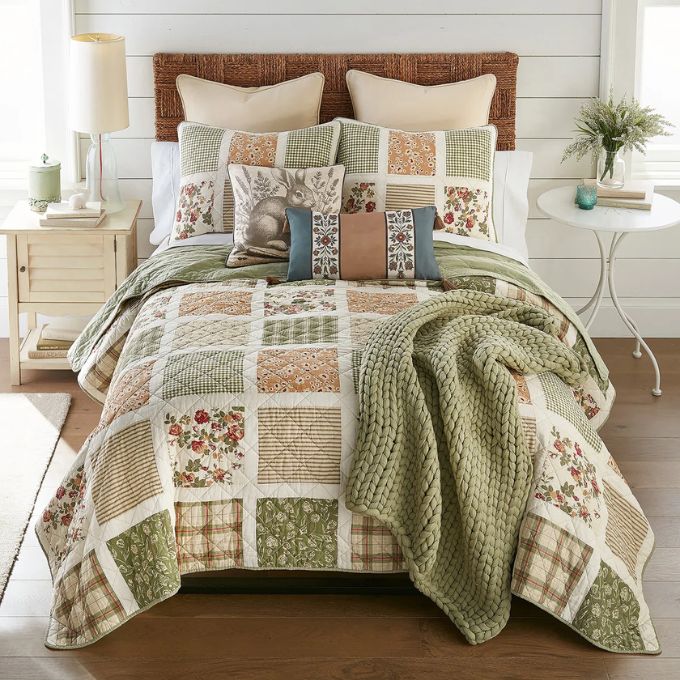 Bed with patchwork quilt and decorative pillows in a bedroom setting. Peach Rose Toss Pillows - Set of Two available at Quilted Cabin Home Decor.
 