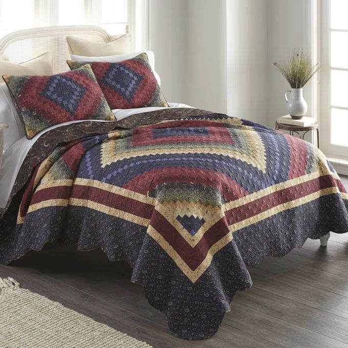 Bed with a colorful quilt and pillows in a bright bedroom. Chesapeake King Quilt Set available at Quilted Cabin Home Decor.