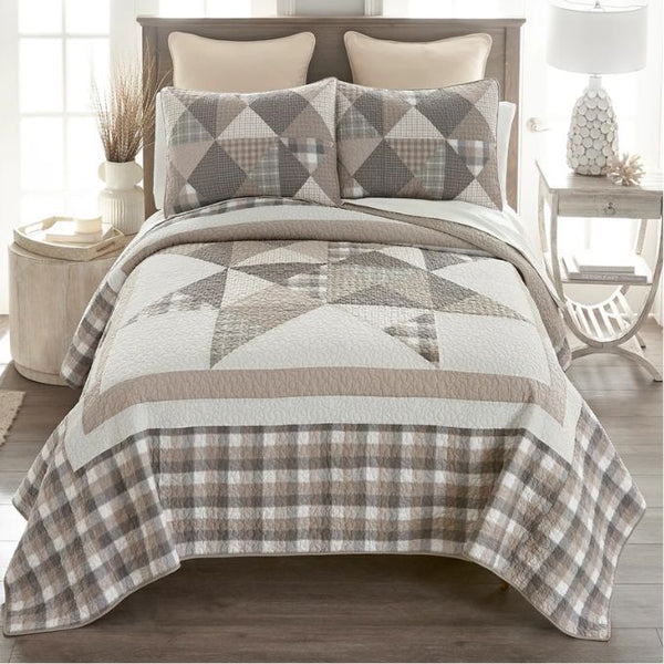 Bed with a geometric patterned quilt and pillows in a bedroom setting. Smoky Star Queen Quilt Set available at Quilted Cabin Home Decor.