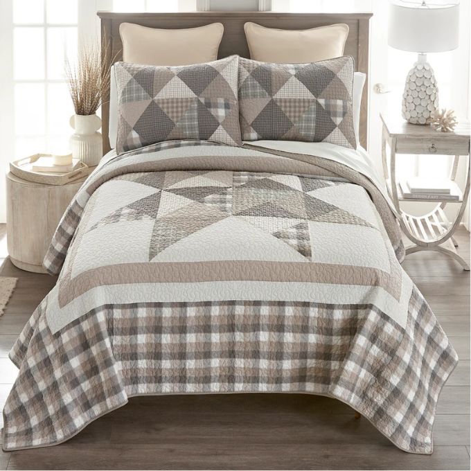 Bed with a geometric patterned quilt and pillows in a bedroom setting. Smoky Star Queen Quilt Set available at Quilted Cabin Home Decor.