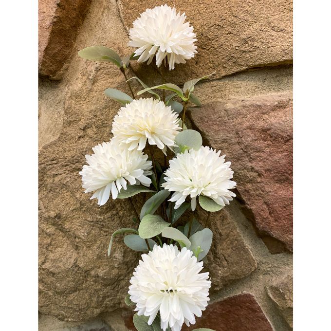 Artificial white flowers with green leaves against a stone wall background. Amaranth Floral Stems - Three Colours available at Quilted Cabin Home Decor.