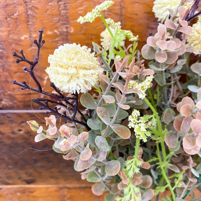Bouquet of artificial plants with a wooden background. Cream Pincushion Floral Spray available at Quilted Cabin Home Decor.