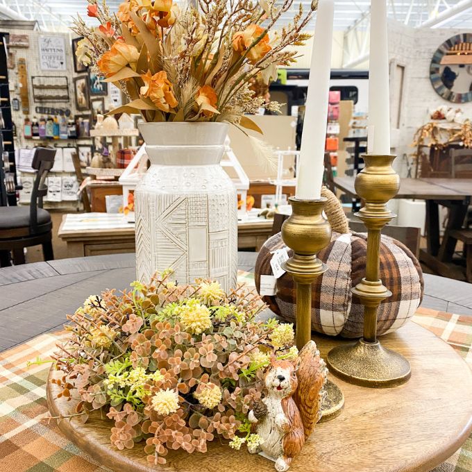 Decorative table setting with flowers, pumpkins, and candles in a store setting. Cream Pincushion Half Floral Sphere available at Quilted Cabin Home Decor.